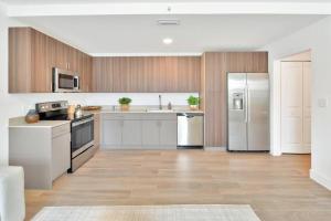 沃思湖Gardenia - The Designer Apartment的一间配备了白色家电和木制橱柜的大厨房