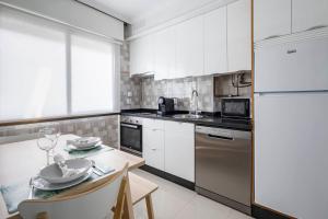 维戈Oporto 4的厨房配有白色橱柜和一张带餐具的桌子。