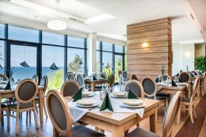 里沃日落Spa酒店的餐厅设有木桌和椅子以及大窗户。