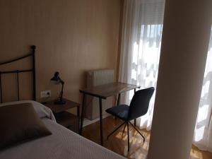 潘普洛纳Apartamento Sadar的一间卧室配有书桌、椅子和床