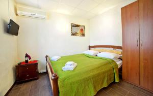 敖德萨马里那拉酒店的一间卧室设有绿色的床和木制橱柜。