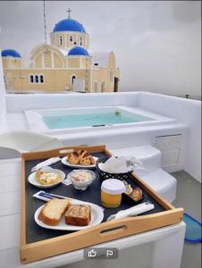费拉Eternity Suites Santorini的游泳池前桌上的食品托盘