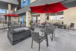 舍伍德帕克TownePlace Suites by Marriott Edmonton Sherwood Park的一个带桌椅和红色遮阳伞的庭院