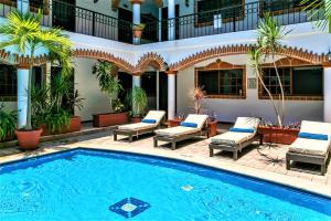 普拉亚卡门Hotel Colonial Playa del Carmen的庭院内的游泳池,带椅子,大楼