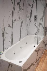 格拉斯哥S.H Apartments的设有带白色浴缸的大理石墙浴室