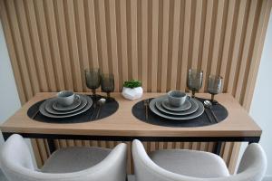 雅典URBAN SUITES ATHENS的一张木桌,带盘子和杯子,椅子