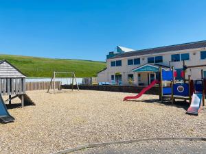 Newquay Bay Resort170 Newquay Bay Resort的一个带两个秋千和滑梯的游乐场
