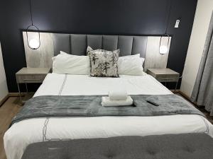 LeribeEmpire Bed & Breakfast的卧室配有一张带两张桌子的大型白色床