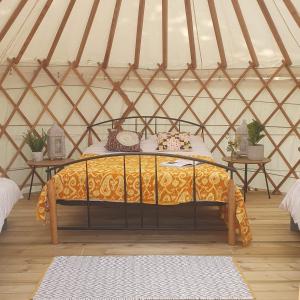塔洛The Lawn Yurt的圆顶帐篷内的一张床位,配有两张桌子