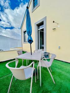 伊利亚武Plaza House Ílhavo的庭院配有桌椅和遮阳伞。