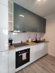 克拉科夫Nowoczesny apartament dla par的厨房配有白色橱柜和黑炉灶烤箱。