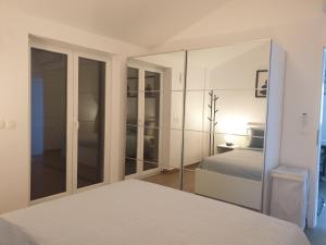 斯楚雅Seafront Apartment Strunjan的白色卧室配有床和镜子