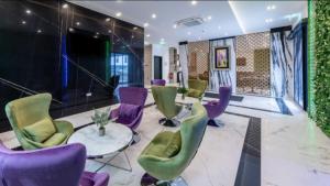 辛德尔芬根Hotel Business Bay das ehemalige Staycation Hotel的大堂设有紫色和绿色的椅子和一张桌子