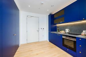 伦敦Apartment Near Canary Wharf 02 Arena & Excel的厨房铺有木地板,配有蓝色橱柜。
