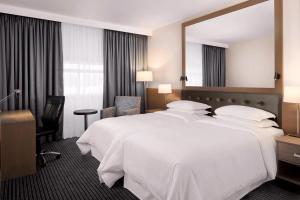 希灵登喜来登希斯罗酒店的酒店客房设有一张白色大床和镜子