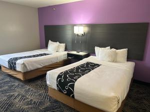 奥马哈西南拉昆塔奥马哈酒店的紫色墙壁的酒店客房内的两张床