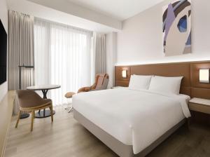 首尔首尔江南SODOWE大使美居酒店的酒店客房设有一张白色大床和一张桌子。