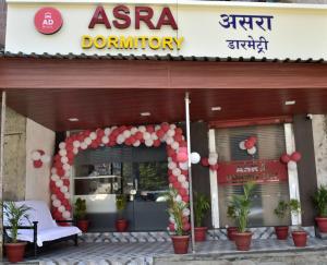 孟买ASRA DORMITORY For Male And Female的红白标志和植物的商店前