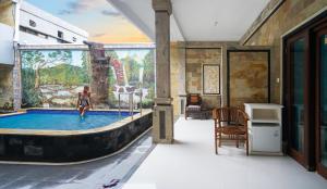 图兰奔AERO氧程巴厘岛潜水度假酒店的站在游泳池的女人,在壁画室里