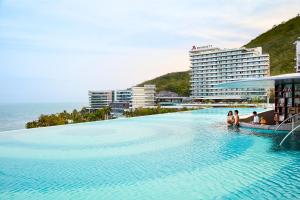 三亚三亚山海天大酒店，傲途格精选（万豪国际旗下酒店）的一座大型游泳池,旁边的人坐在游泳池里