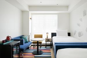 大阪Aloft Osaka Dojima的酒店客房,设有两张床和一张蓝色的沙发