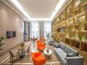 秦皇岛凯里亚德酒店秦皇岛南戴河店的图书馆配有橙色椅子、沙发和桌子