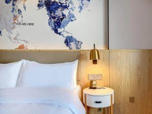 哈尔滨凯里亚德酒店(哈尔滨西站万达广场店)的一间卧室,配有一张床和一张世界地图
