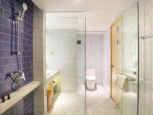 哈尔滨凯里亚德酒店(哈尔滨西站万达广场店)的一间带卫生间和玻璃淋浴间的浴室