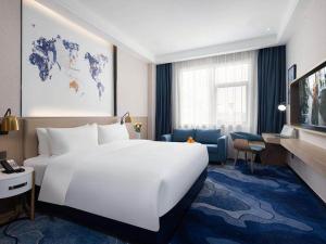 宝安凯里亚德酒店(深圳机场固戍地铁站店)的酒店客房设有一张白色大床和一张书桌