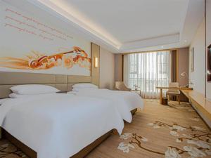 南昌维也纳国际酒店南昌青山湖万达广场店的酒店客房设有四张床,墙上挂有绘画作品