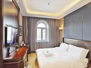 哈尔滨凯里亚德酒店哈尔滨火车站中央大街店的卧室设有一张白色大床和一扇窗户。