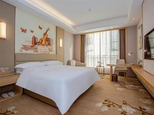 南昌维也纳国际酒店南昌青山湖万达广场店的卧室配有一张白色大床和一张书桌