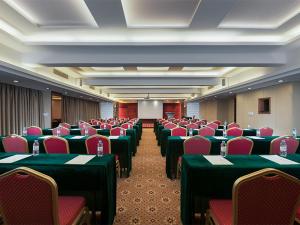 清远维也纳酒店清远城市广场连江路店5.0的一间会议室,配有绿色的桌子和红色的椅子