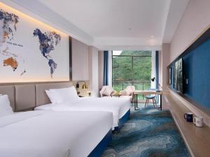 贺州凯里亚德酒店(贺州万达广场店)的酒店客房设有两张床,墙上挂有一张世界地图。