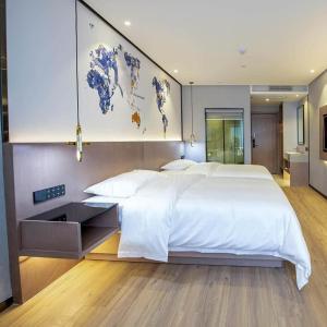 惠州凯里亚德酒店大亚湾比亚迪科技园店的卧室配有一张大白色床,墙上挂有地图