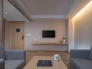 东莞凯里亚德酒店(东莞黄江金怡店)的客厅配有两张沙发、一张桌子和一台电视机