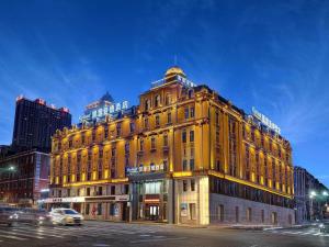哈尔滨凯里亚德酒店哈尔滨火车站中央大街店的夜幕降临的城市街道上一座黄色的大建筑
