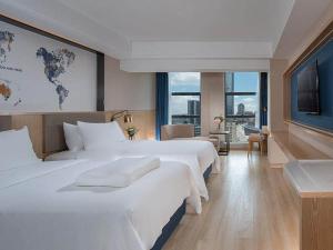 惠州凯里亚德酒店(惠州南站淡水壹中心店)的酒店客房设有两张床和大窗户。