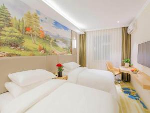 牡丹江维也纳智好酒店牡丹江火车站步行街店的酒店客房设有两张床,墙上挂有绘画作品