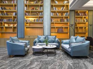 信阳凯里亚德酒店(信阳平桥店)的图书馆,设有两张沙发、一张桌子和书架