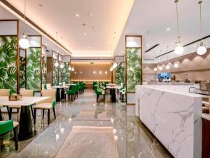 长沙凯里亚德酒店 (长沙芙蓉广场地铁站店)的一间带桌子和绿色椅子的餐厅和一间酒吧