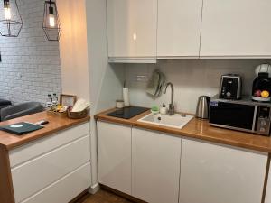 奥古斯图Sosnowe Apartamenty - Marina.的厨房配有白色橱柜、水槽和微波炉