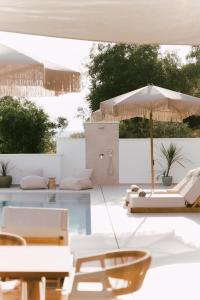 帕尔加Merelia Exclusive Villas的一个带白色家具和遮阳伞的游泳池