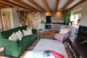 埃文河畔斯特拉特福Piglet's Hideaway的一间带绿色沙发的客厅和一间厨房