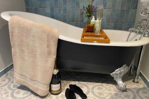 埃文河畔斯特拉特福Piglet's Hideaway的带浴缸和一瓶香槟的浴室