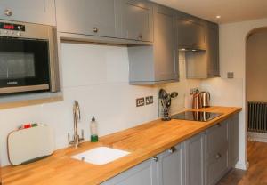 威尔汉姆Cosy Modern Cottage - Wareham的厨房配有木制台面和水槽