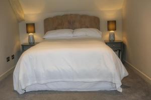 威尔汉姆Cosy Modern Cottage - Wareham的一间卧室配有一张带2个床头柜的大型白色床