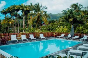 巴斯特尔马兰加花园酒店的一个带椅子和棕榈树的游泳池以及围栏
