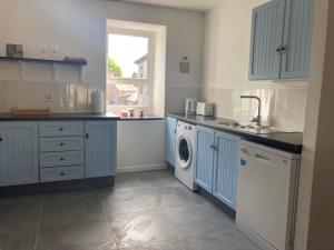 斯温福德Kilaturley house apartment的厨房配有蓝色橱柜和洗衣机。