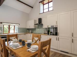 布里斯托Swallow Barns的厨房配有白色橱柜和一张带椅子的木桌